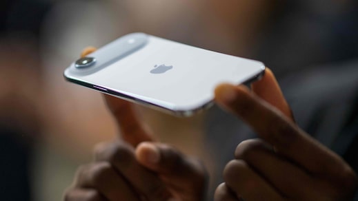Pessoa segurando iPhone em uso com interface do aparelho visível