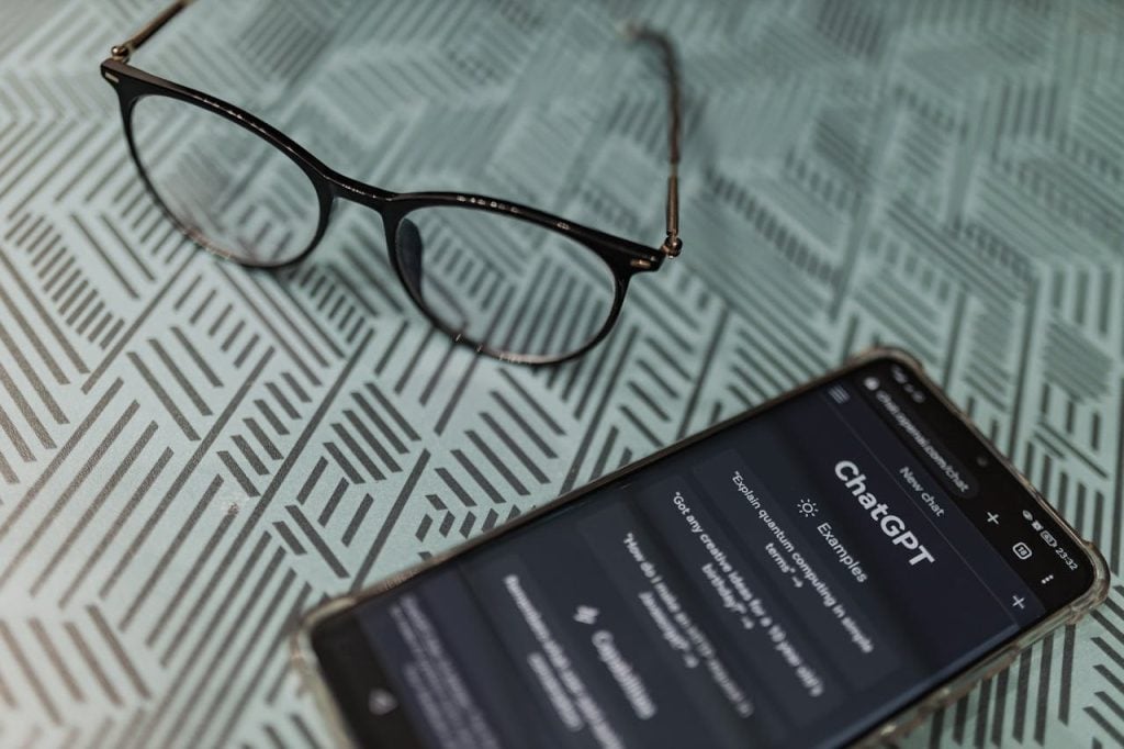 Smartphone exibindo aplicativo de IA estilo ChatGPT sobre mesa