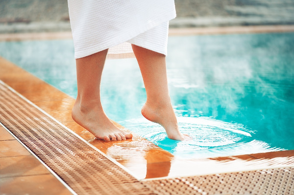 Pessoa tocando a água de uma piscina para sentir a temperatura
