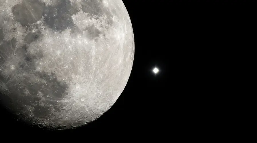 Uma foto do céu noturno mostrando a Lua e Vênus bem próximos no quadro, com destaque para o contraste de brilho entre os dois astros e um enquadramento que valorize a composição visual do encontro.